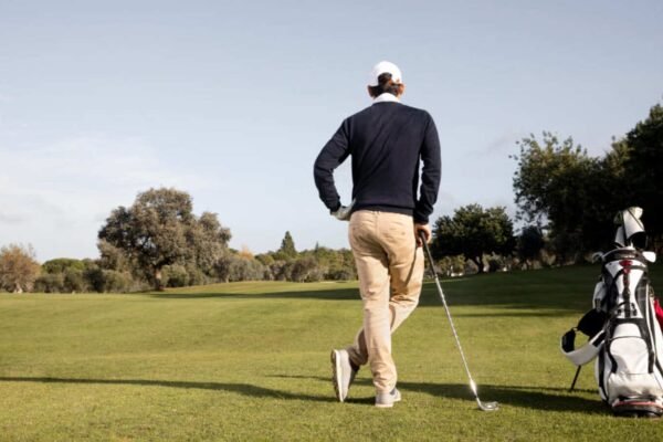 Hombre Jugando golf en Querétaro parado junto a su mochila con los palos y accesorios.