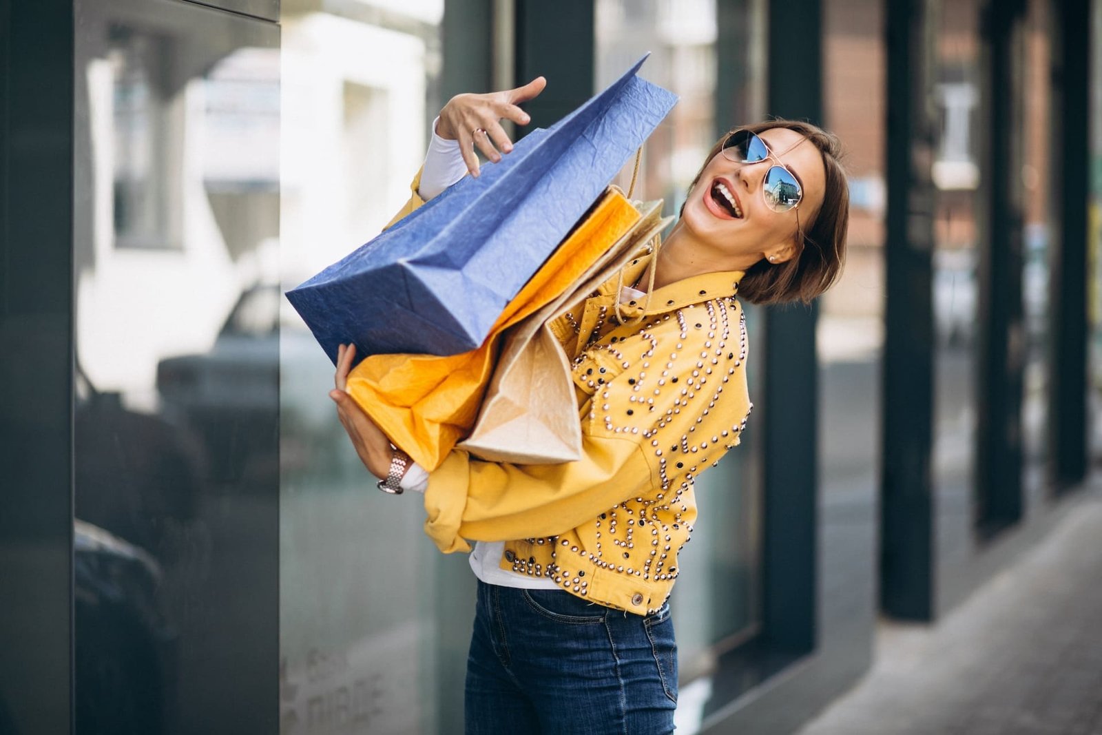 saliendo de Centros Comerciales en Querétaro con bolsas en sus manos sonriendo feliz con gafas de sol