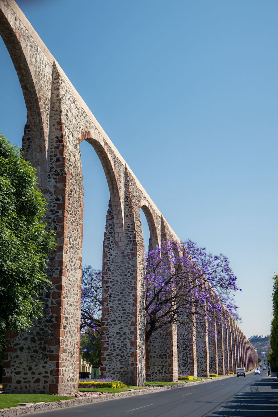 queretaro-mexico-aqueduct-with-jacaranda-tree-and-obra de arcos hechos de piedra poderoso queretaro-mexico-acueducto