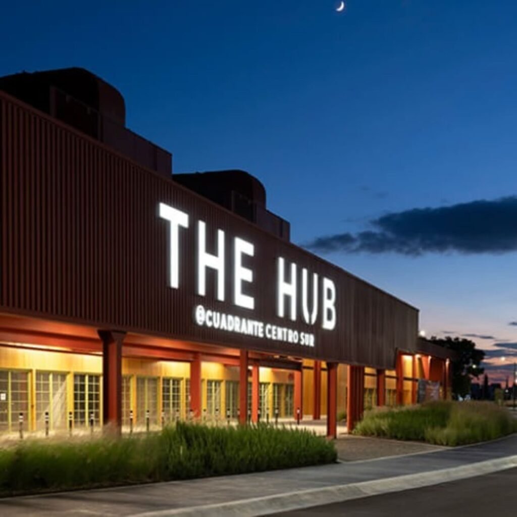 Fachada iluminada de The Hub Querétaro al anochecer.