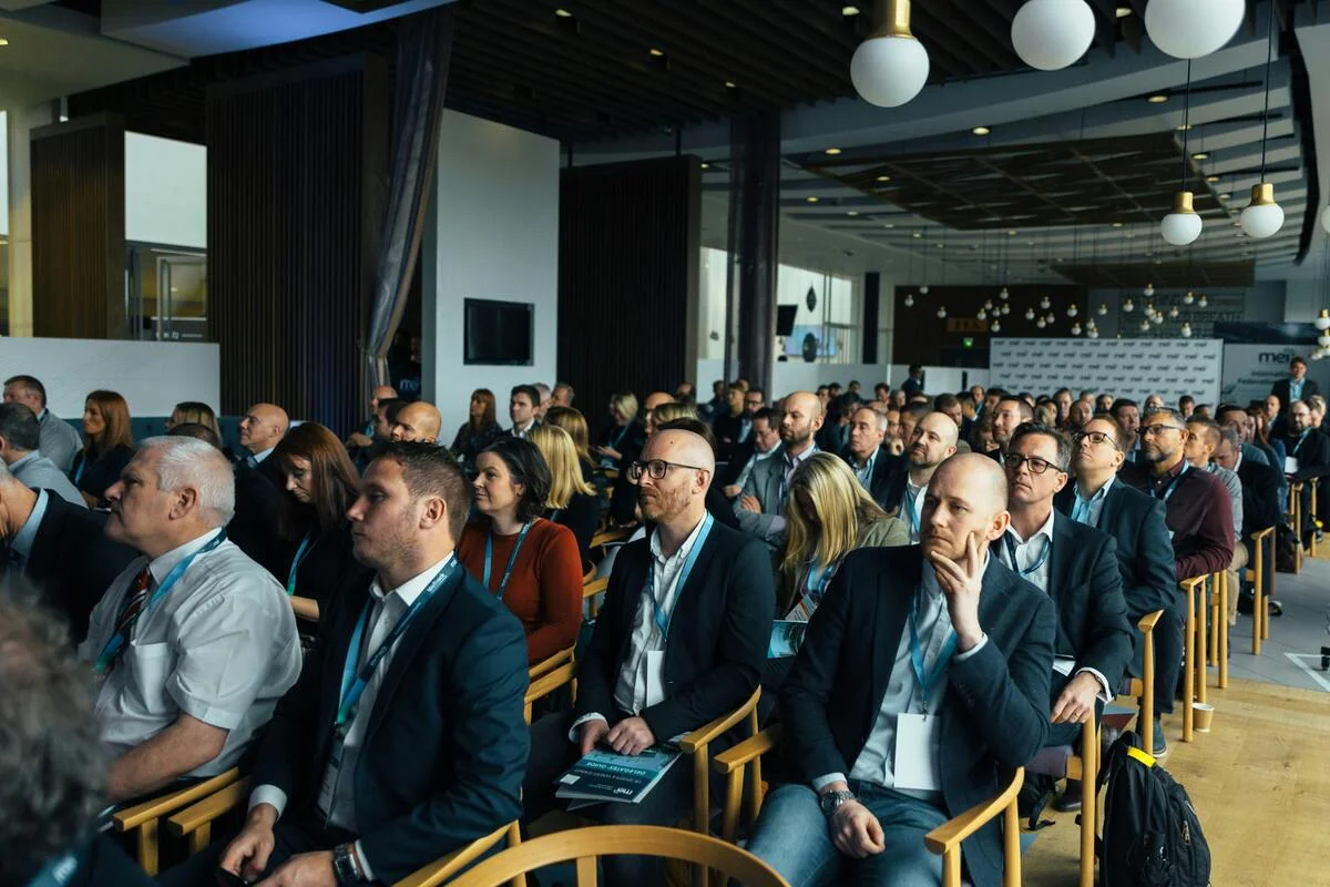 Asistentes atentos durante una conferencia en un salón de eventos.