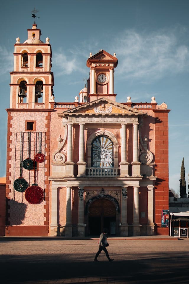 Toma frontal retirada de la Parroquia de Santa María de la Asunción en Tequisquiapan, mostrando la iglesia completa junto con el entorno de la plaza.