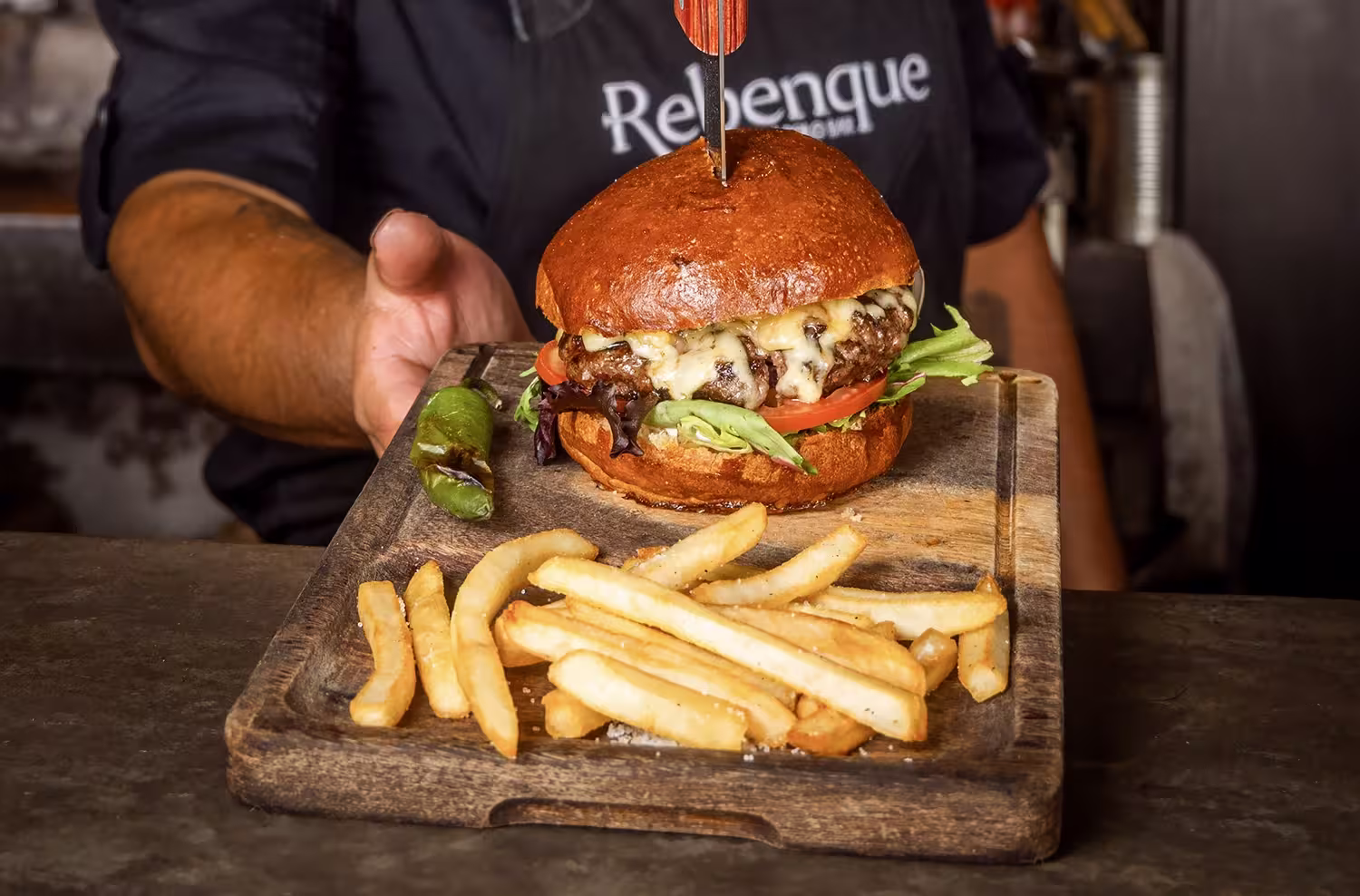 Hamburguesa de Lujo en Rebenque, Viñedos del Polo | Restaurante Exclusivo en Querétaro Hamburguesa artesanal servida en el restaurante Rebenque, Viñedos del Polo, Querétaro, acompañada de papas fritas y jalapeño asado.