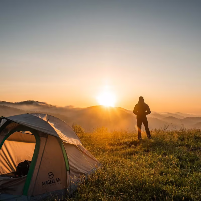 Persona acampando en el Mirador Cuatro Palos contemplando el amanecer sobre la Sierra Gorda en Querétaro, México