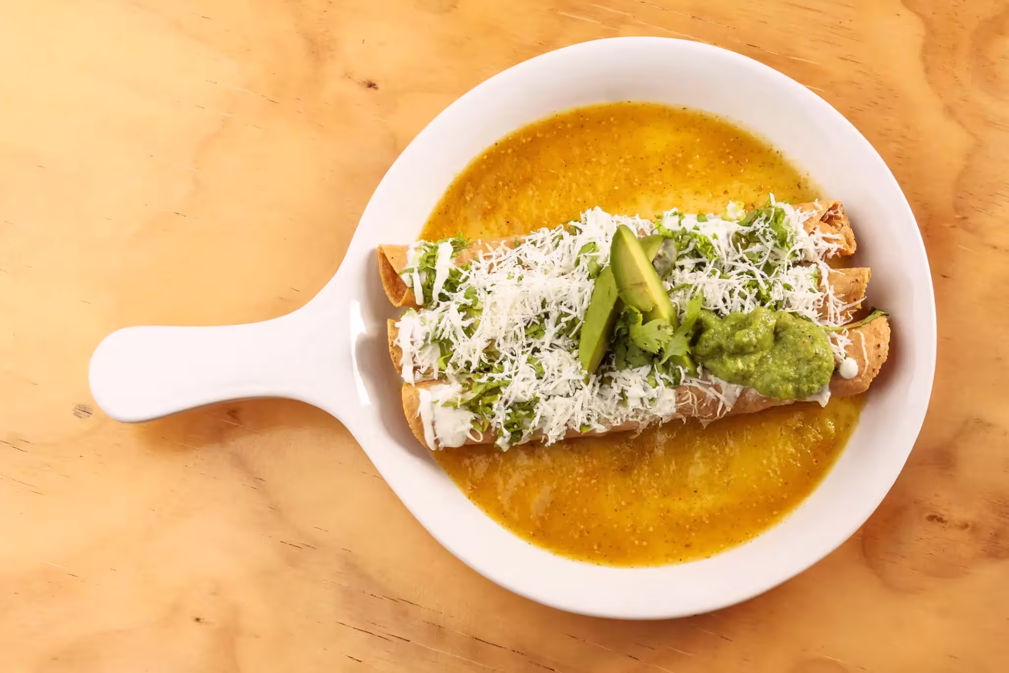 Tacos dorados con salsa de chile morrón | Color, sabor y tradición mexicana Tres tacos dorados mexicanos bañados en salsa de chiles morrones, con crema, queso rallado y aguacate