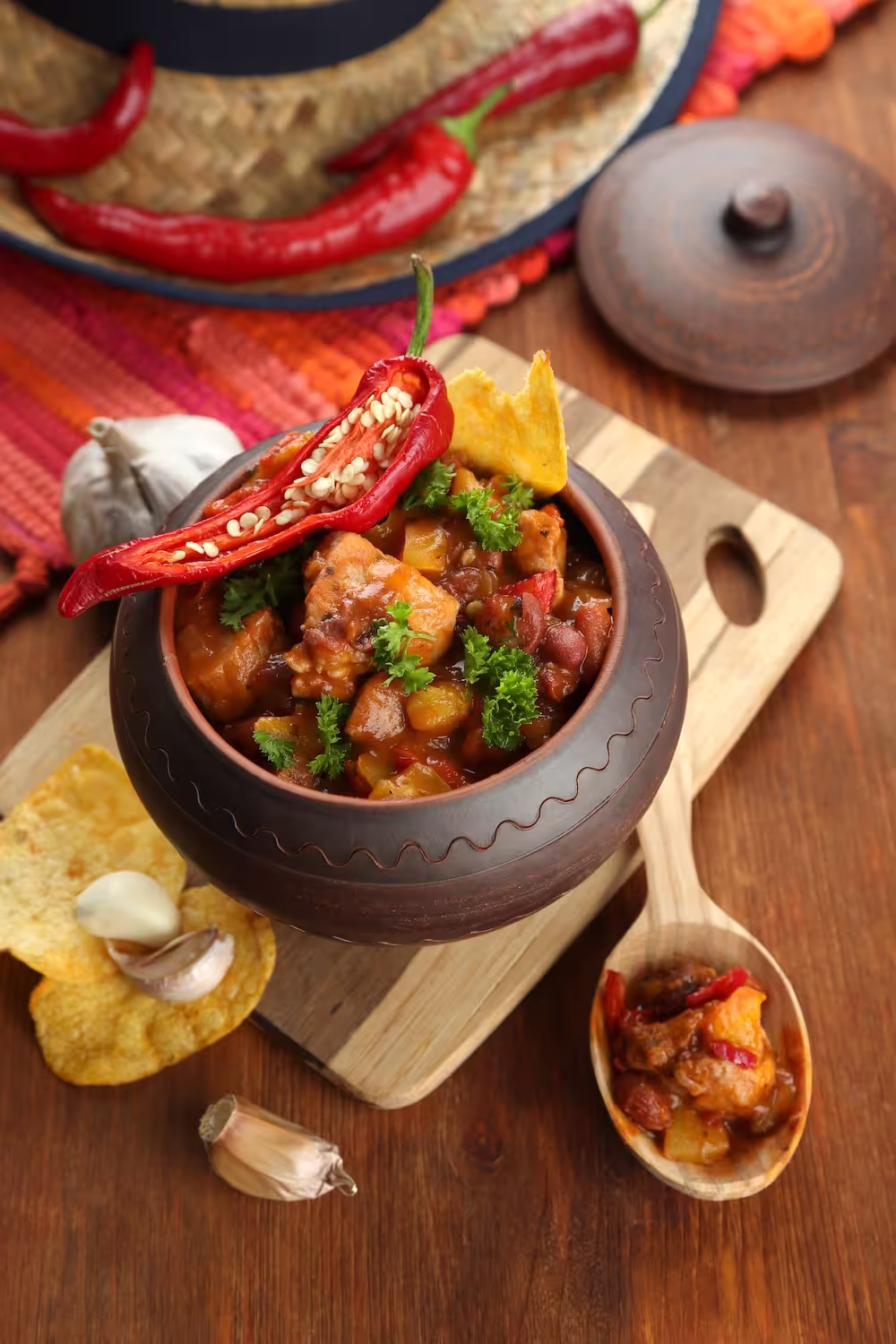 Platillo tradicional de chili con carne servido en olla de barro sobre fondo rústico