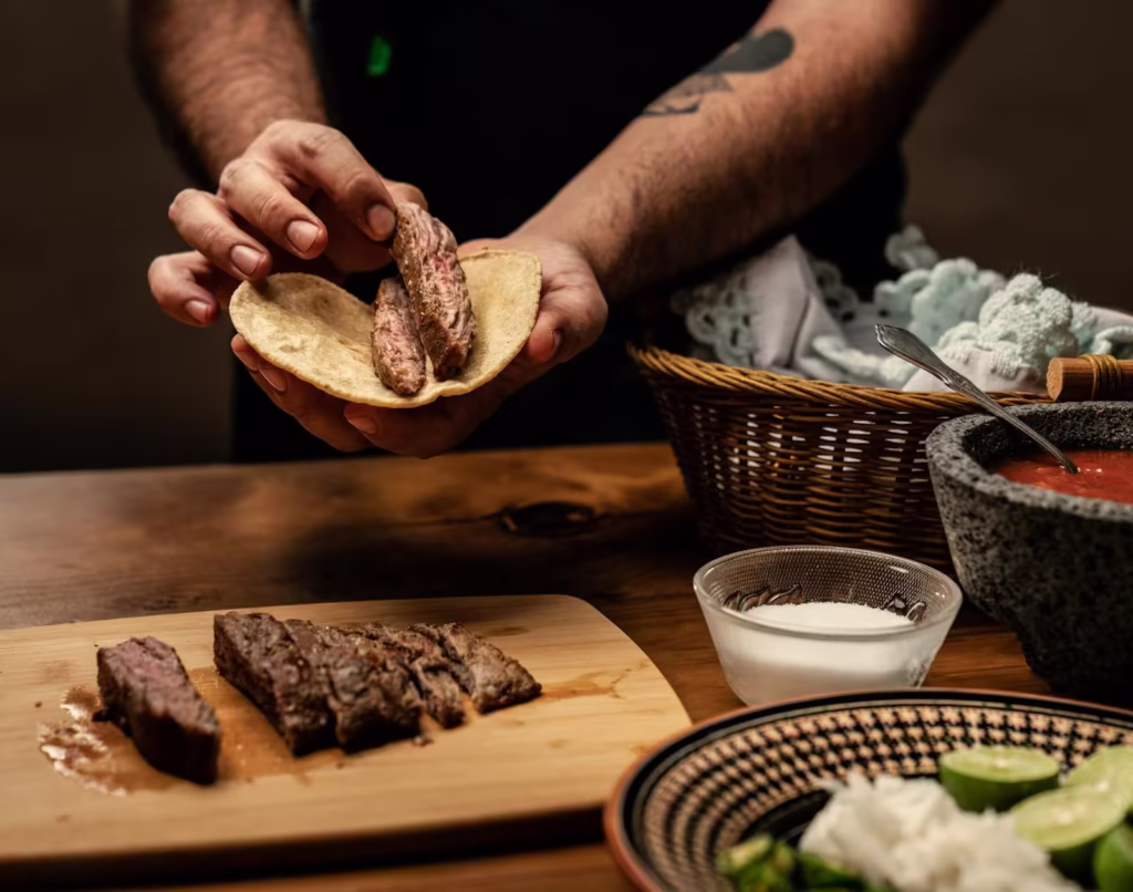 cortando en tabla de madera trozos de carnitas cocitas para tacos en taqueria de queretaro