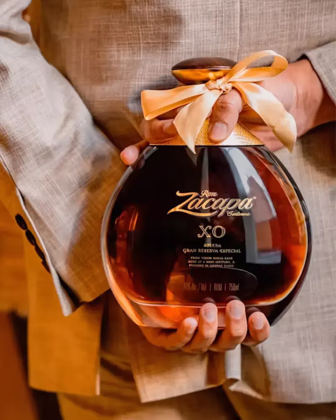 Ron Zacapa Centenario servido en copas de cristal tallado sobre una mesa de lino gris oscuro