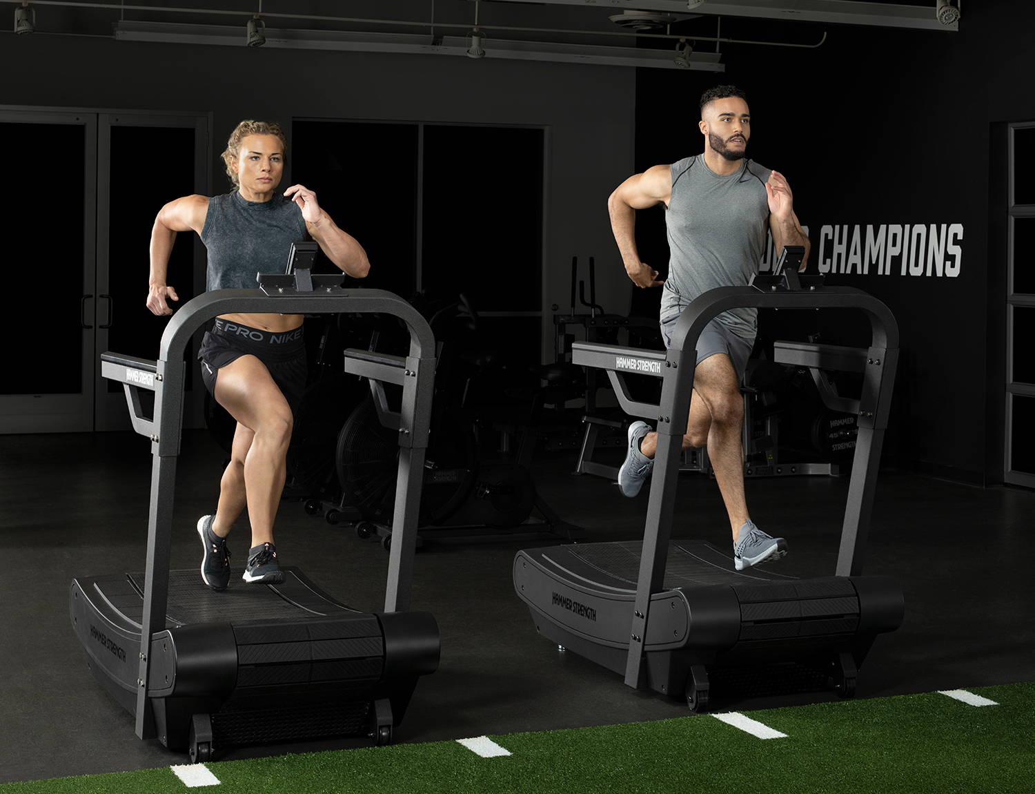 Dos atletas entrenan en caminadoras curvas Hammer Strength HD Tread