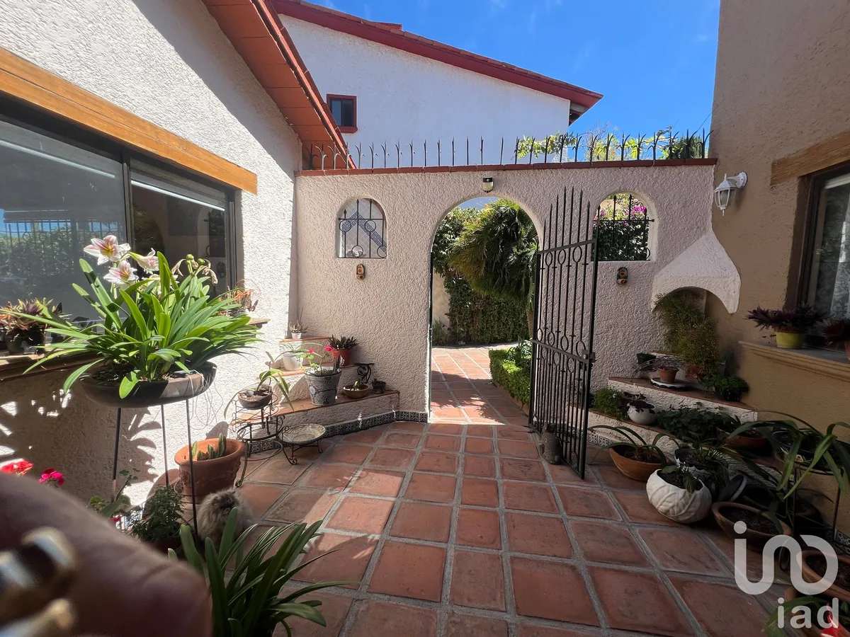Patio de acceso con arco, plantas y piso de barro de la casa en Vista Real
