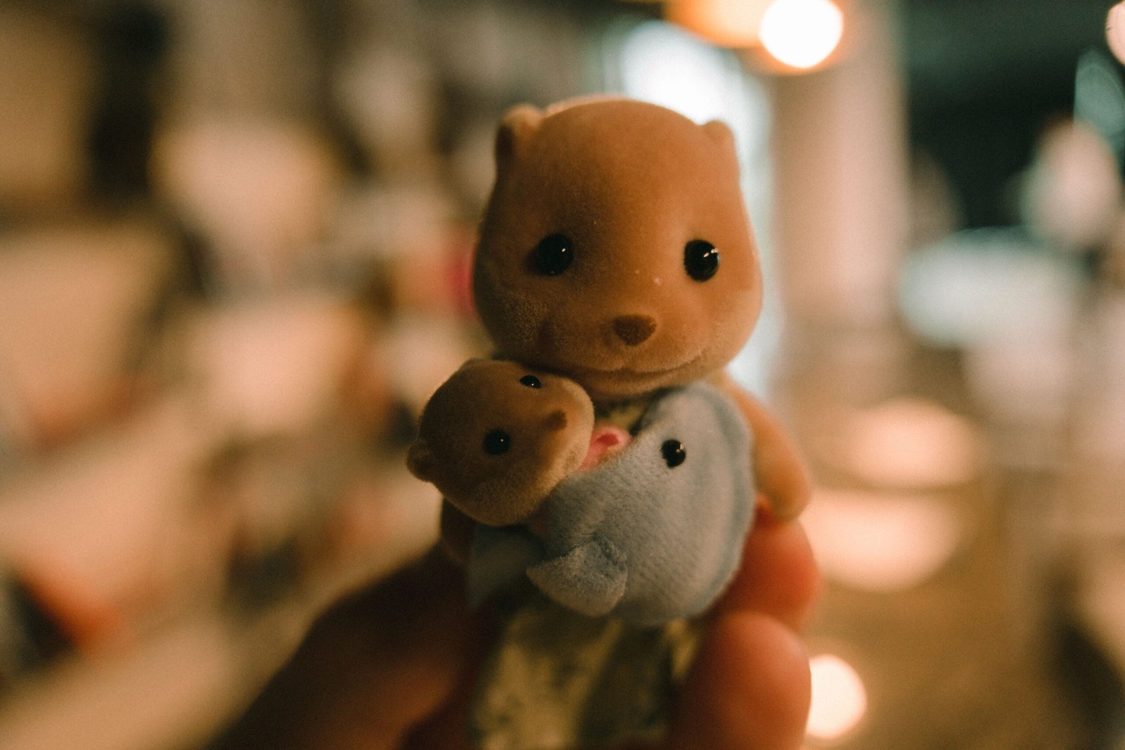Una mano sostiene un pequeño oso de peluche