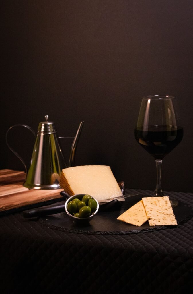 Copa de vino tinto con quesos, aceitunas y galletas